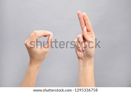 Woman showing word okay on grey background, closeup. Sign language