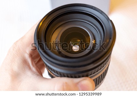 Hand holding and look through the lens at light background