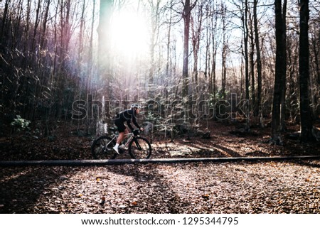 pretty female cyclist on a road bike rides in a nature mountain forest. sporty woman exercise outdoor. moody picture of girl cycling 
