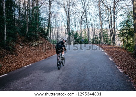 pretty female cyclist on a road bike rides in a nature mountain forest. sporty woman exercise outdoor. moody picture of girl cycling, in motion