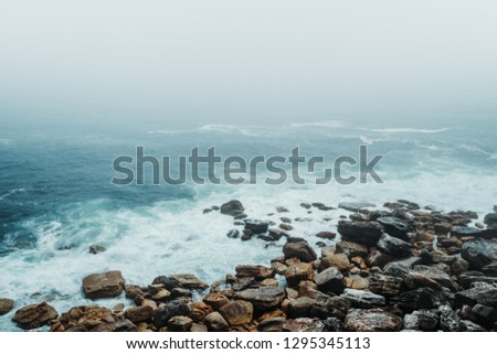 A moody scene of Ocean Mist on a Rocky Shore