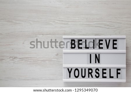 'Believe in yourself' words on lightbox on a white wooden surface, top view. From above, flat lay, overhead. Copy space.