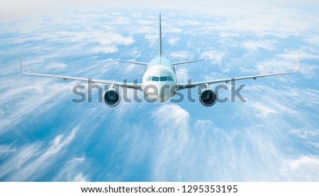 An airplane is flying over low clouds and  blue sea