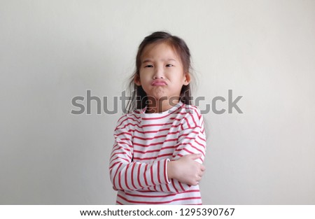 Asian Little girl is angry And cross one's arm with white background.