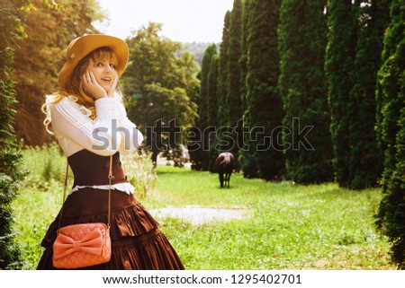 Beautiful girl in a hat in a vintage dress walking in a Summertime park