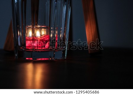 Candle in glass cup on wooden background