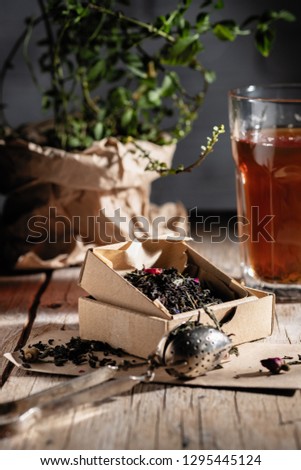 fragrant tea with fruits and flowers in kraft packaging on the table decorated with a pot of mint