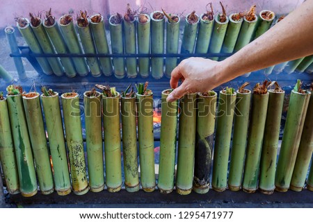 Thai food,make glutinous rice with coconut milk roasted in a length bamboo joints cylinder,Burned sticky rice with sweet coconut milk in bamboo shot,Sticky rice and coconut milk in bamboo.