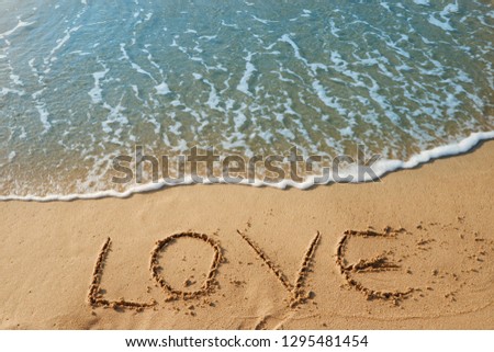 The word writing love on sand beach with blue waves background. 