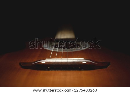 part of an old brown guitar with strings on a dark wooden background. Selective focus Royalty-Free Stock Photo #1295483260