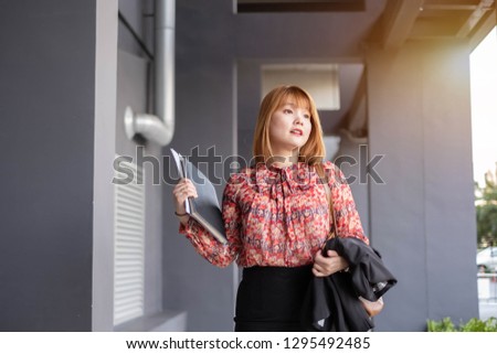 An Asian woman walk happily to work. This portrait picture can be used in such concept as financial, investor, businesswoman, working woman, boss, commuter, out for lunch, finish work, go home.   