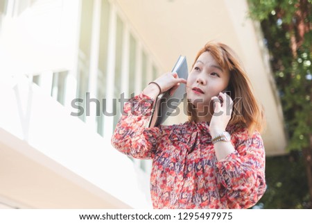 A busy Asian woman walking to work while talking on a phone . This portrait picture can be used in such concept as  hurry businesswoman, working woman, boss, commuter, out for lunch, finish work.  