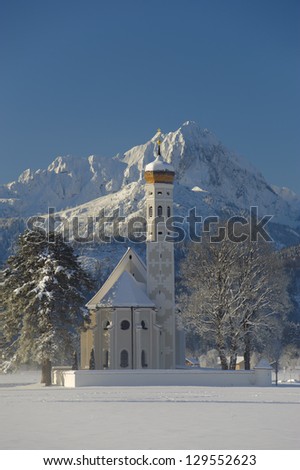 famous church St. Coloman in upper bavaria, germany, at winter with snow and alps mountain in background