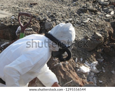 Worker with white protective suit, gloves and mask removes removal white asbestos on construction site. Demolition building, caution hazard. Action picture, part of a serie.   