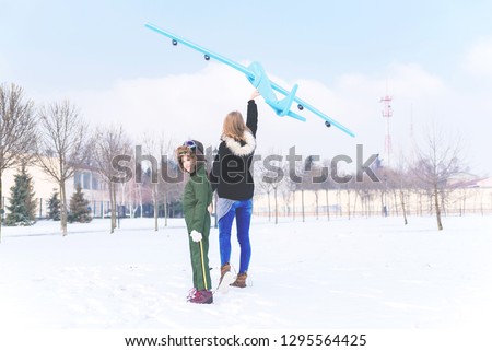 Cute little kid enjoying beautiful snowy winter day with mother in park