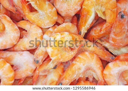 Pink frozen royal shrimps with ice. Boiled unpeeled seafood close up background