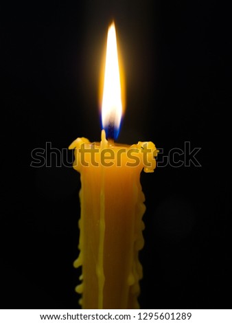 The burning wax candle shines in the dark