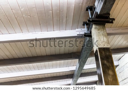 wooden ceiling with beams and support that holds it at an angle from the bottom