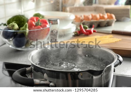 Pot with boiling water on electric stove in kitchen, closeup