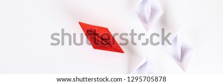 Red paper boat among other white. Leadership, white crow, individuality. Piranhas and a shark. Not like everyone else. Origami. Top view, flat lay, copy space