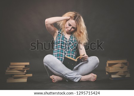 pretty blonde caucasian student girl so tired to learn, she sits with many books and unhappy