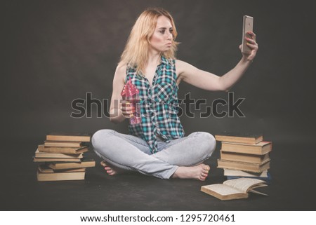 teen girl sitting on the floor next to books, does not want to learn, drinking juice and taking a selfie on the smartphone