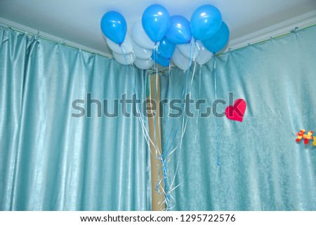 Helium balloons . Sky and white balloons float on the white ceiling in the room for the party. Sky and white or children birthday party decoration interior .