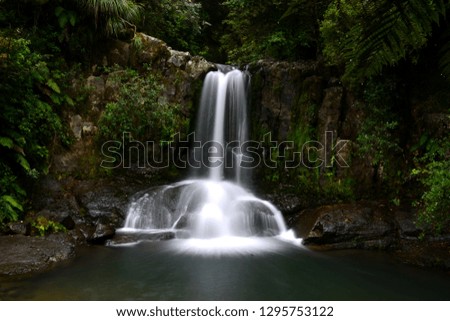 water fall in the bush over a pool, in new zealand aotearoa,  