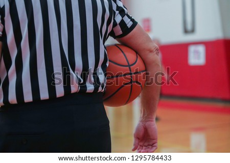 A basketball referee holds a ball during a timeout