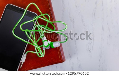 Internet audiobook reading book, smartphone, headphones on the background of a wooden table