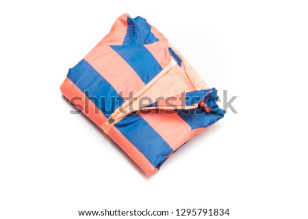 Folded blue and orange zipper windbreaker jacket, rain proof jacket hoodie. Track jacket sport shiny nylon full zip isolated on white. Folded clothes.