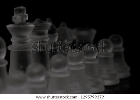 Queen and other chess pieces in close up with dark blur background