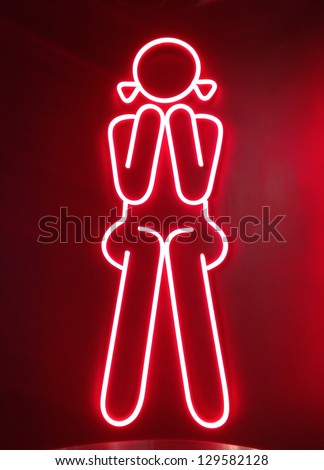 red neon sign for girl sitting in front of  female toilets