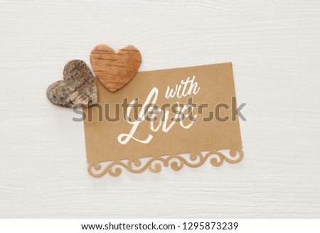 Valentine's day concept. hearts cutted from tree trunk and vintage paper note over wooden white background