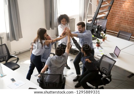 Above top view diverse multiracial millennial colleagues giving high five feels happy and proud achieved goal celebrating successful completion of project expressing support togetherness team spirit