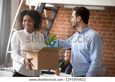 Happy attractive excited mixed race female holding carton box with stuff feel happy at first workday. Boss ceo introduce to coworkers newcomer colleague employee. First impression new job concept Royalty-Free Stock Photo #1295890822