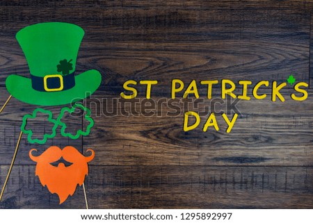 Saint Patrick Day concept. Paper Patrick day leprechaun props: green leprechaun hat, orange beard,orange mustache and lucky clover trefoil as symbol of Ireland traditional holiday on wooden background