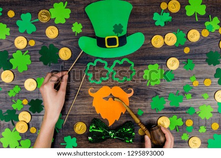 Saint Patrick Day concept. Paper Patrick day leprechaun props: green leprechaun hat orange beard orange mustache and lucky clover trefoil as symbol of Ireland traditional holiday on wooden background