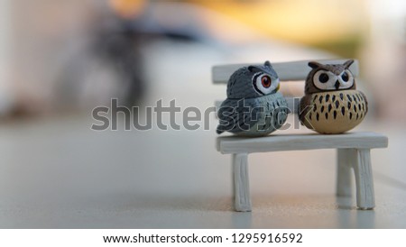 A couple of owls are sitting on a bench