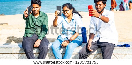 Two men one woman taking selfies at the beach with sea in background. Trendy and fashion light treatment. LAck failure in modern communication concept.