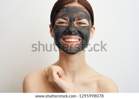 woman smiling in a cosmetic mask made of clay lifting