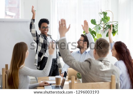 Diverse business people group raise hands at corporate presentation training, happy multi-ethnic employees team participate in vote volunteering, ask questions at conference with african coach leader Royalty-Free Stock Photo #1296003193