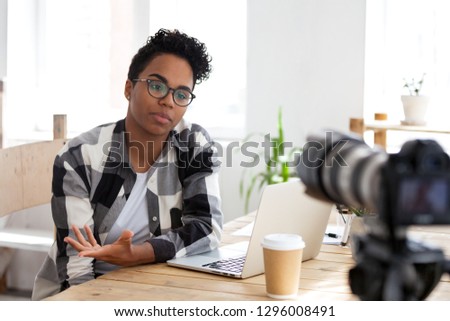 Serious african girl blogger vlogger talking to camera shooting educational video filming webinar blog, black female business coach teacher speaking recording vlog training or job interview