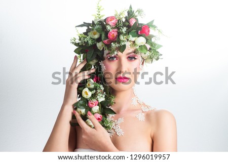 Portrait of a beautiful brunette with huge erect eyelashes in the image of spring with a wreath of roses on his head on a white background.