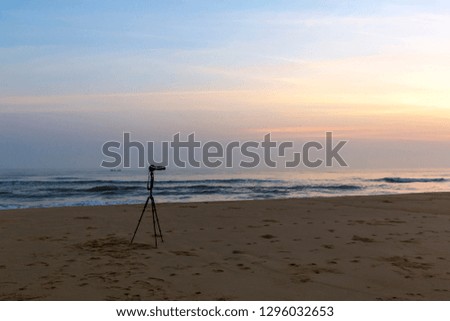 A high quality picture of tripod, camera on the coast at sunset
