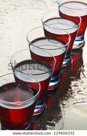 red wine in a transparent glass on a mirror covered with water drops.