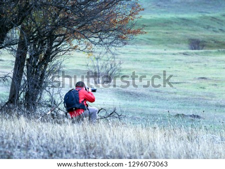 young photographer photographing in mountain valley 