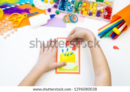 Child makes a postcard with a picture of a cake. Kid paperwork. Material for creativity. Kindergarten and school.