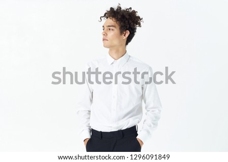 Handsome elegant man with curly hair in a white shirt office worker on a light background
