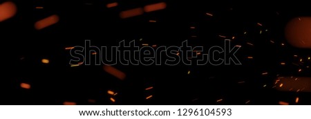 flying sparks from fire in front of black backgound Royalty-Free Stock Photo #1296104593